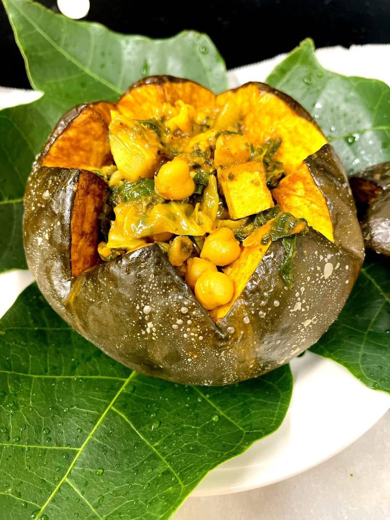 Roasted kabocha squash filled with chickpea curry and greens, on breadfruit leaves