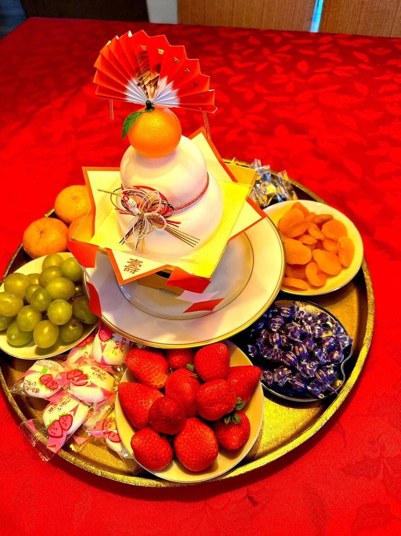 A kagami mochi New Year display surrounded by strawberries, grapes and tangerines