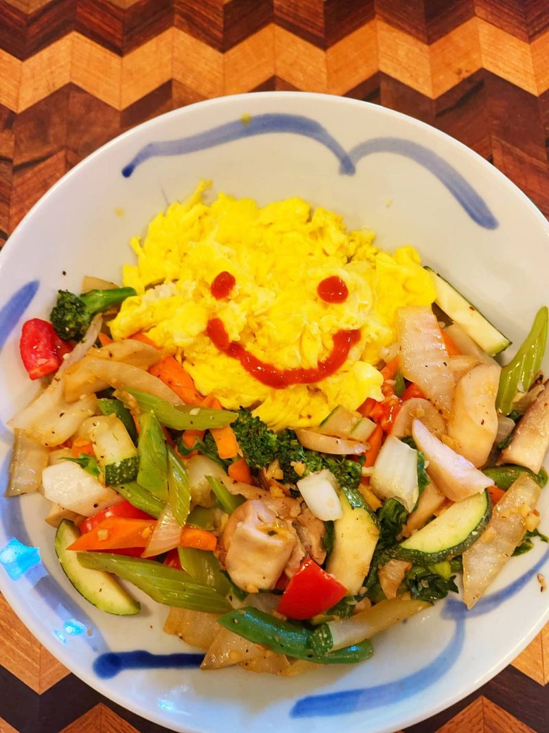 A bowl of stir-fried vegetables with scrambled eggs drawn with a smiley face